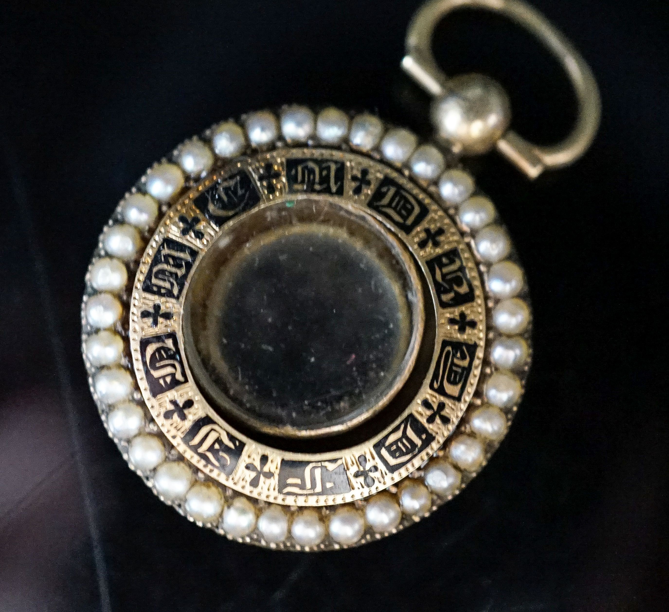 A William IV yellow metal, black enamel and split pearl mounted glazed circular mourning pendant vacant enamelled mourning brooch, 25mm. with engraved inscription, gross 6.5 grams.